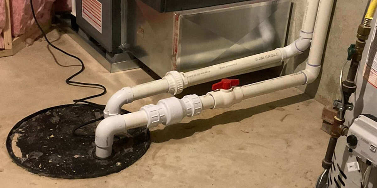 PVC drainage pipes connected to a sump pump in a basement