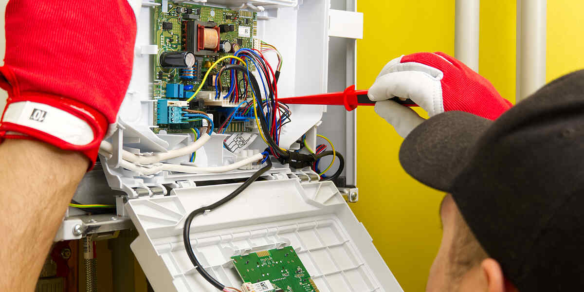 Technician troubleshooting an electrical circuit board with insulated gloves