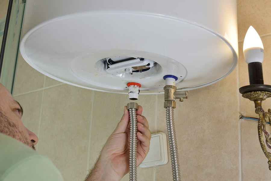 Technician installing water supply lines on a wall-mounted heater